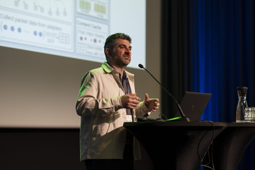 Flavio Esposito speaking at the conference podium.